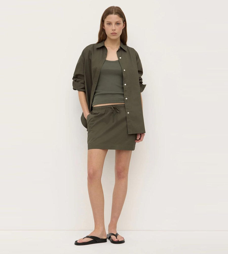 Woman wearing an olive green outfit against a white background