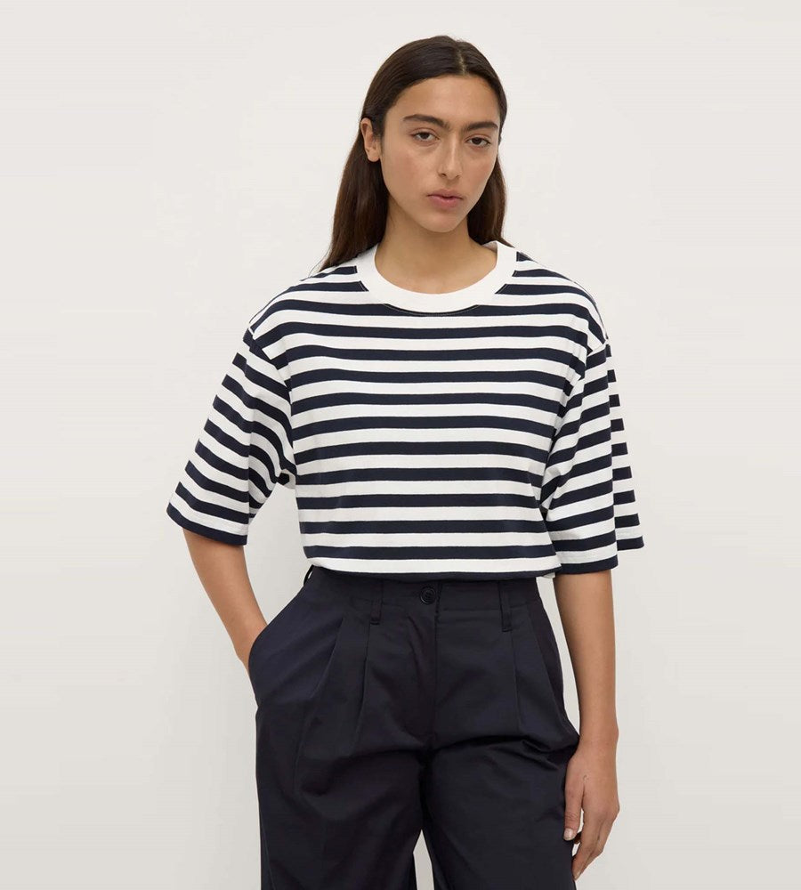 Person wearing a black and white striped shirt with navy pants on a plain background