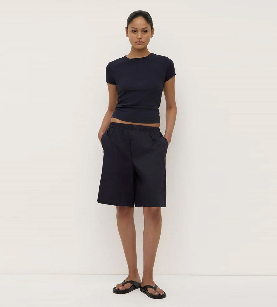 Person wearing a navy blue top and shorts on a white background