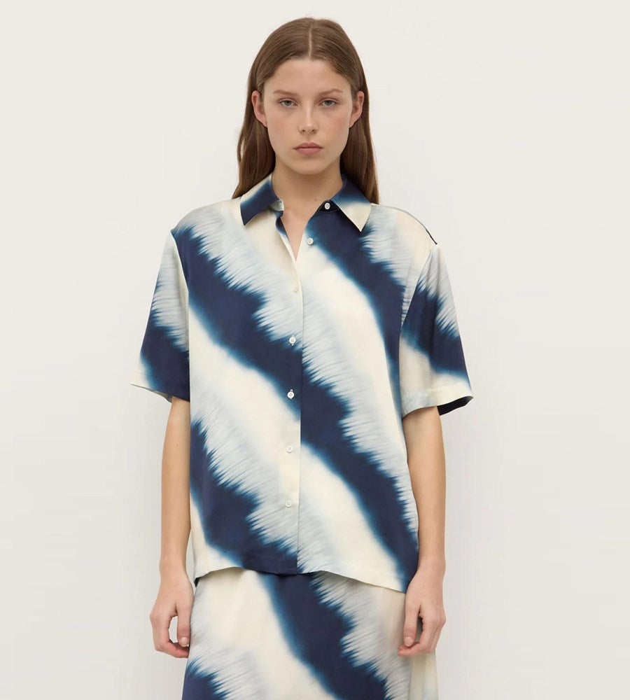 Woman wearing a blue and white tie-dye shirt on a plain background