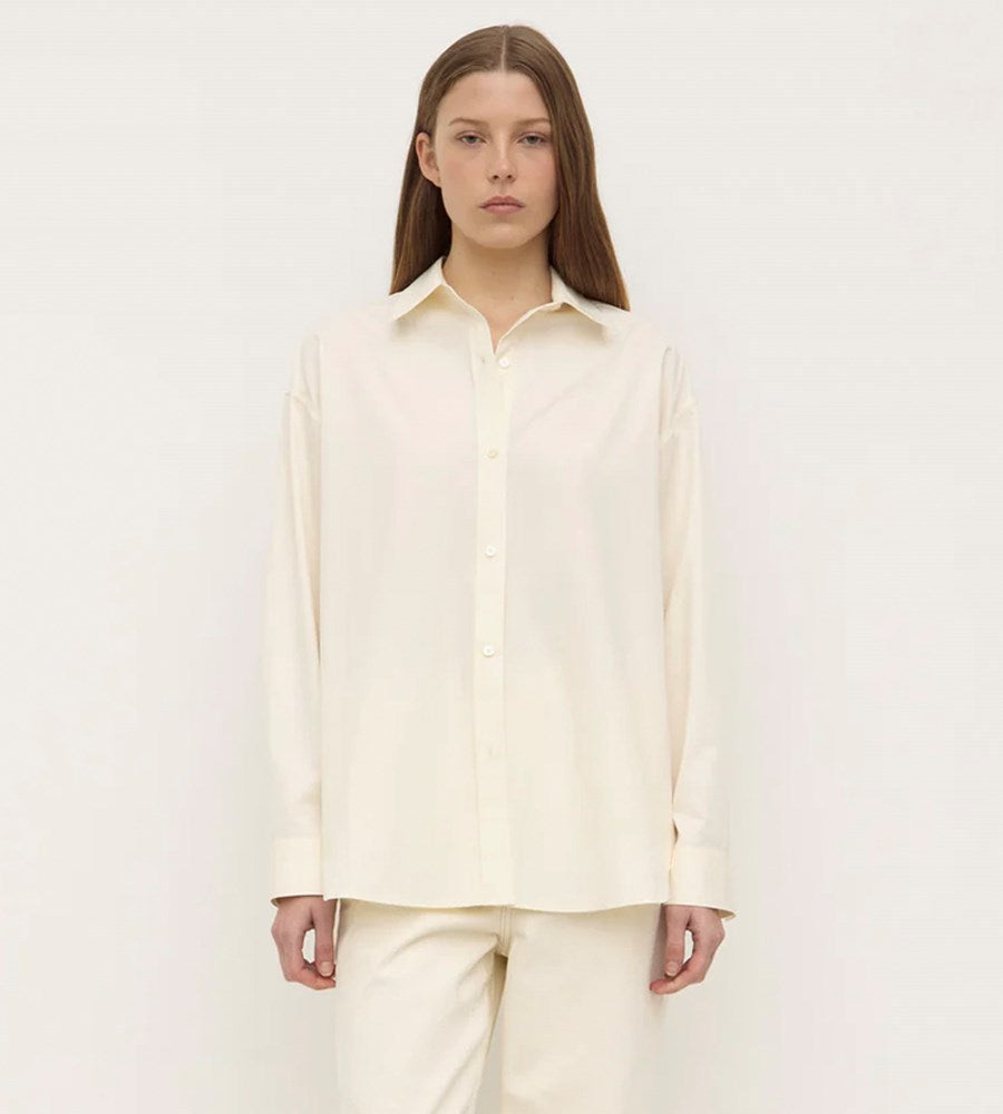 Person wearing a light-colored shirt and pants on a white background