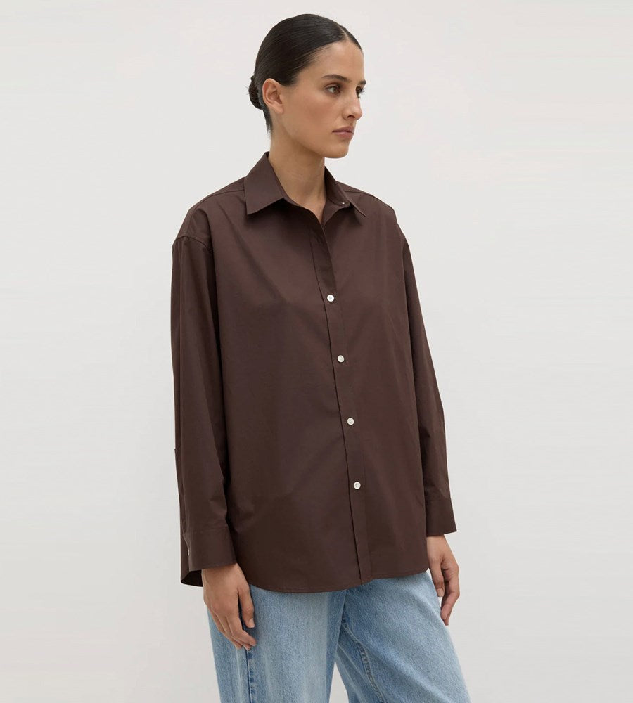 Woman wearing a brown shirt and blue jeans on a white background