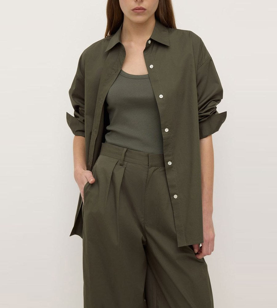 Person wearing an olive green shirt and pants on a plain background
