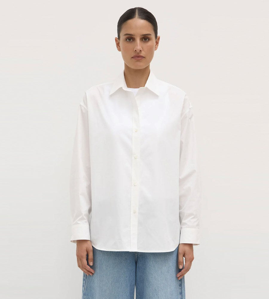 Person wearing a white shirt and blue jeans against a plain background