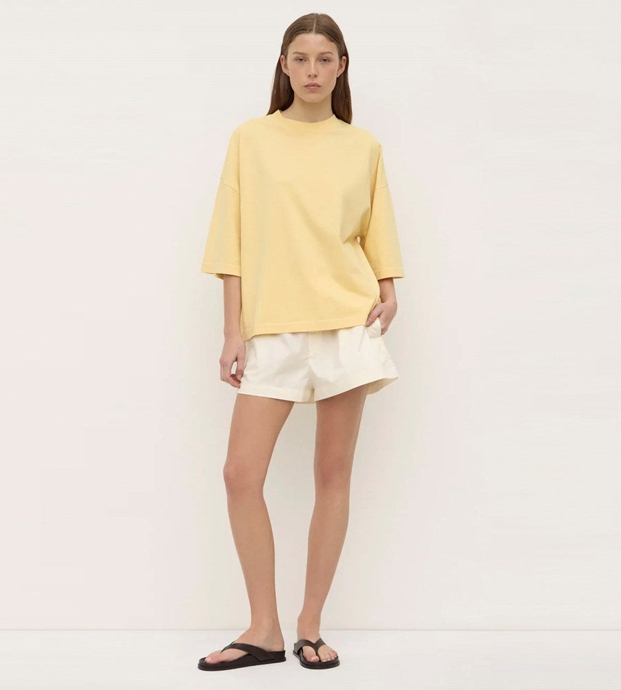 Person wearing a yellow top and white shorts on a plain background