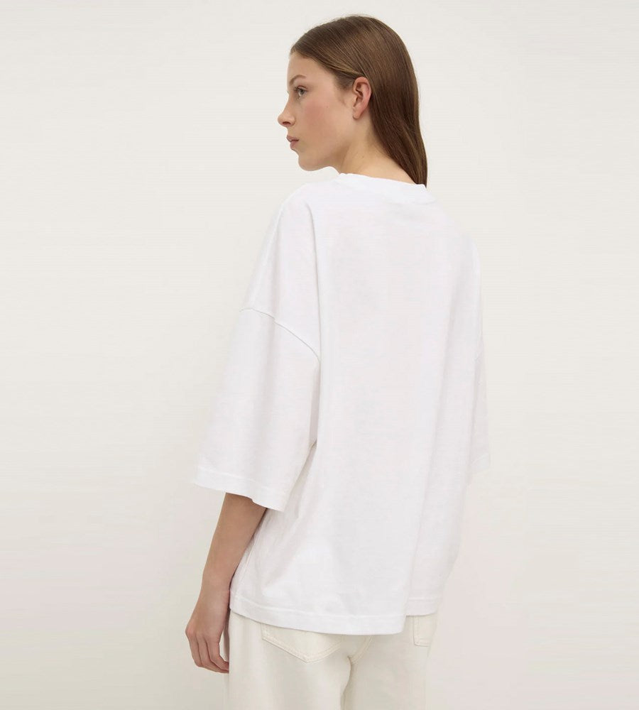 Person wearing a white top and pants against a plain background