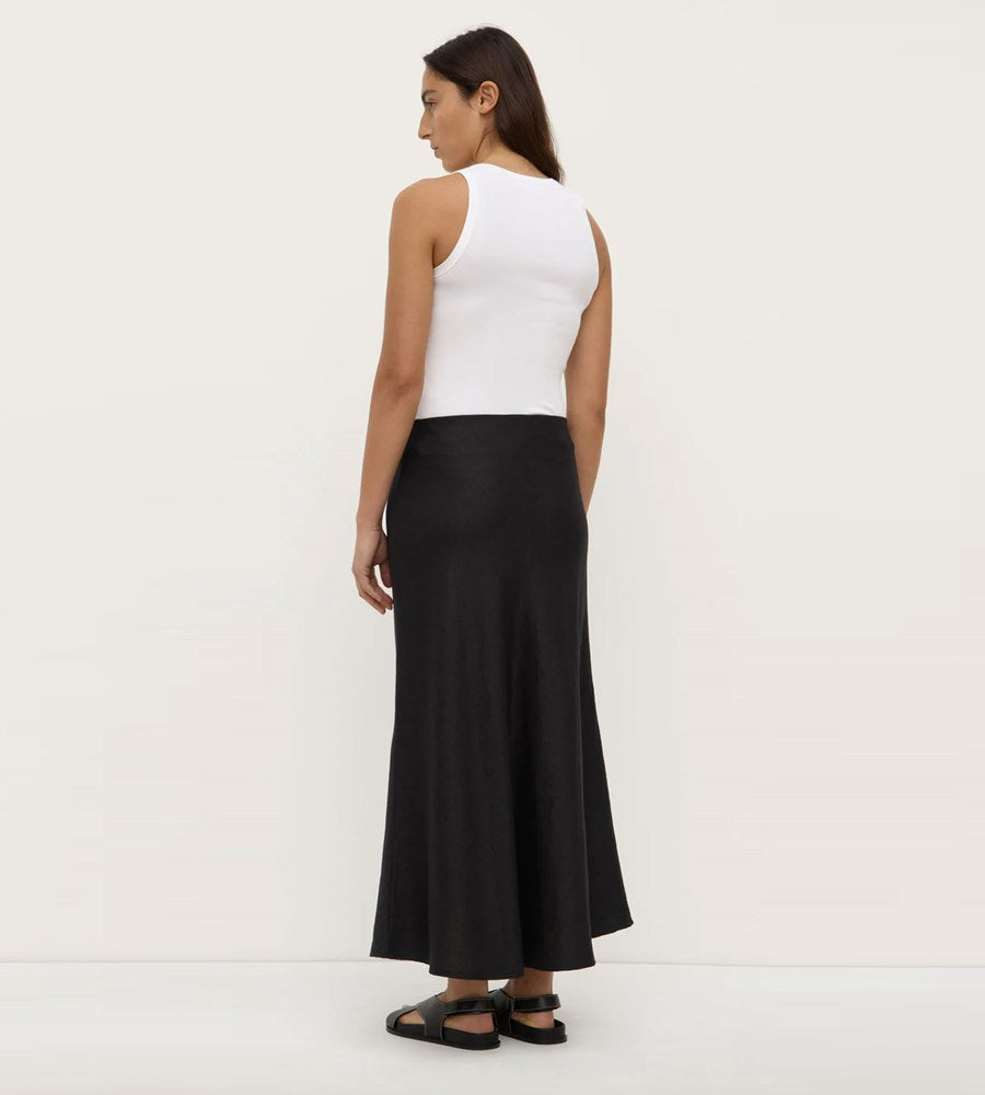 Woman wearing a white sleeveless top and black skirt on a white background