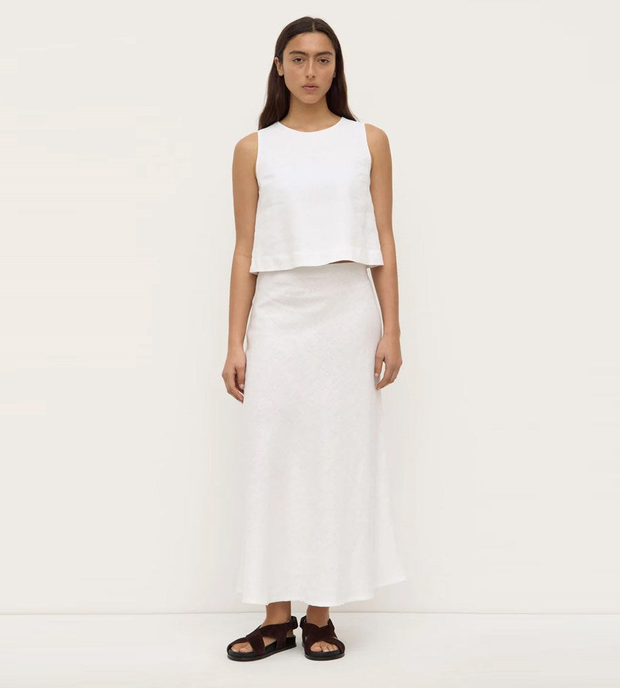 Person wearing a white sleeveless top and white skirt on a white background