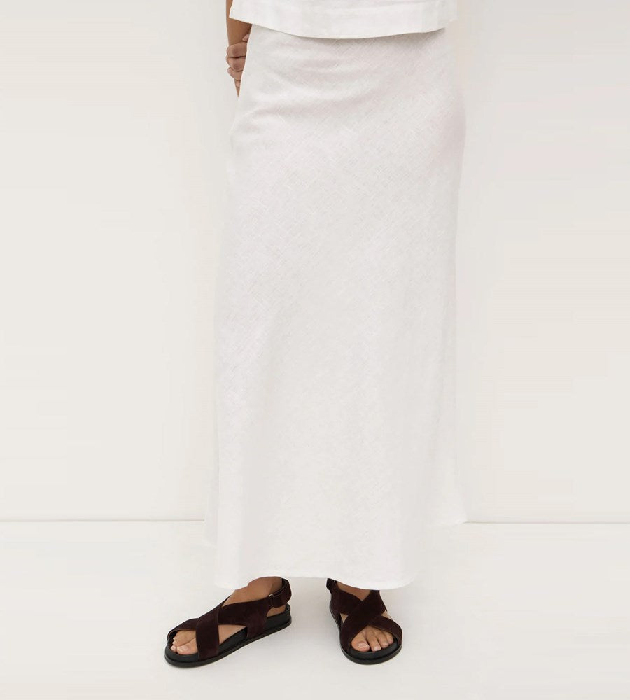Person wearing a white skirt and black sandals on a white background