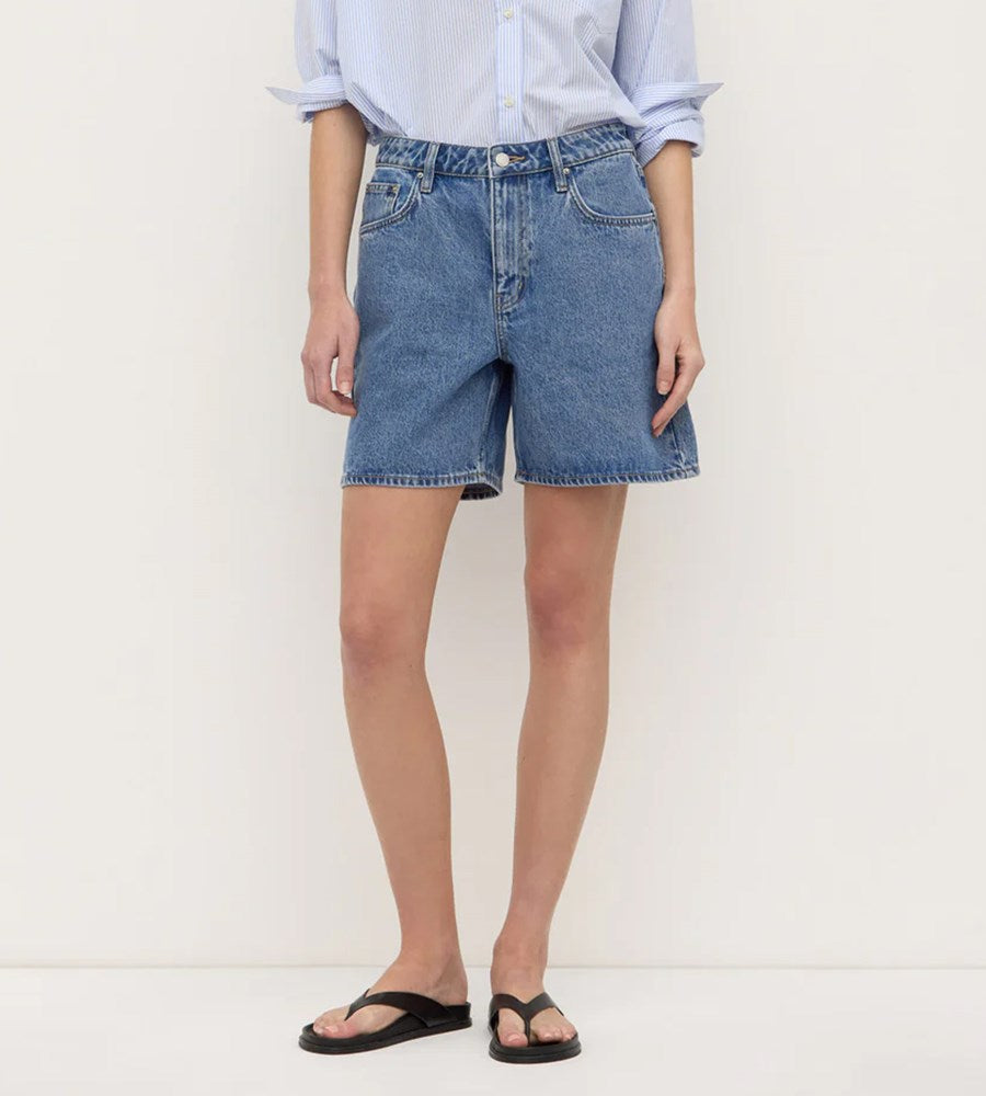 Person wearing blue denim shorts on a white background