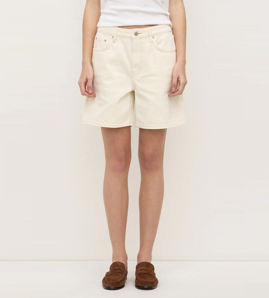 Person wearing a white top and beige shorts on a plain background