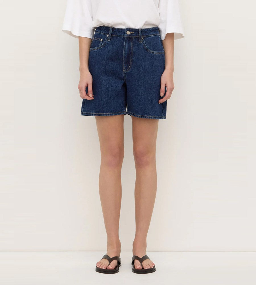 Person wearing blue denim shorts on a white background