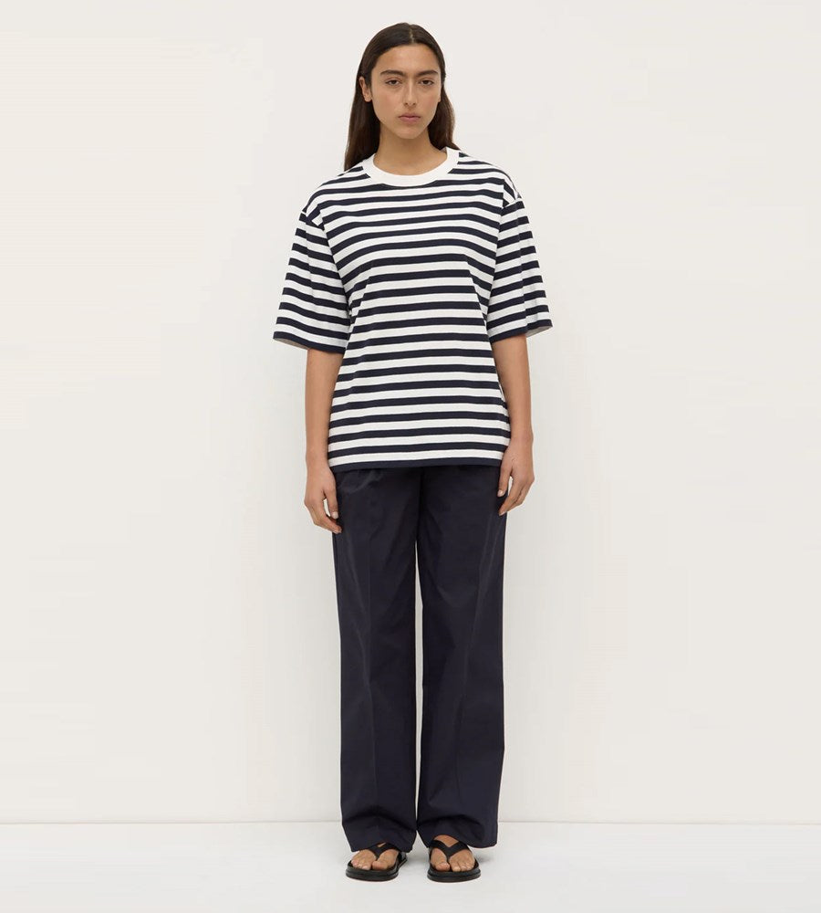 Person wearing a black and white striped shirt and dark pants on a white background