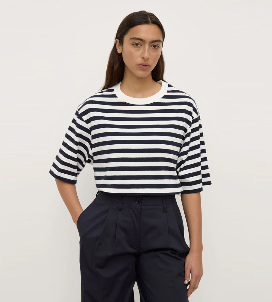 Person wearing a black and white striped shirt with navy pants on a plain background