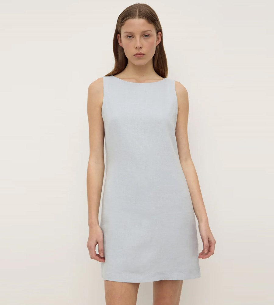 Woman wearing a light blue sleeveless dress against a plain background