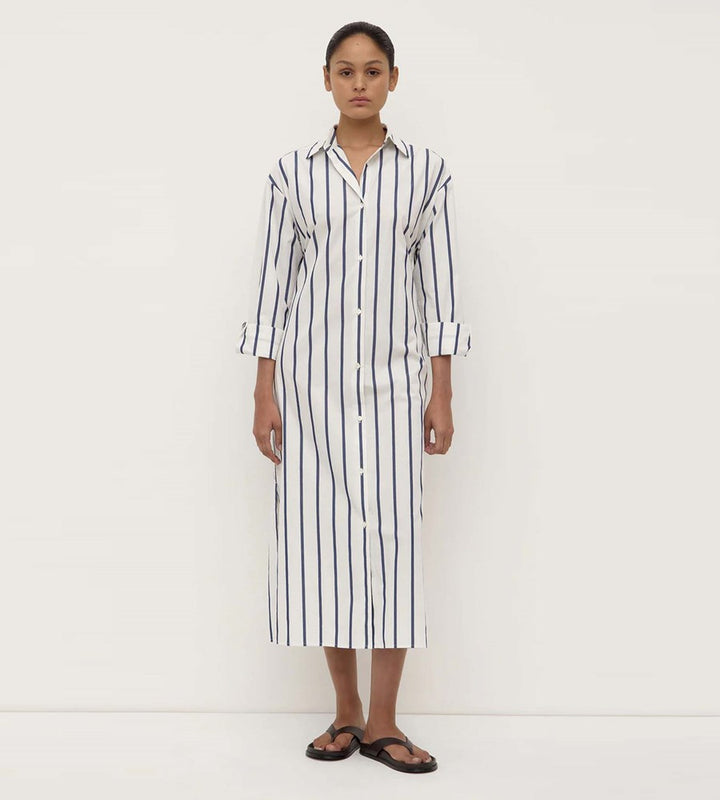 Woman wearing a long black and white striped shirt dress on a white background