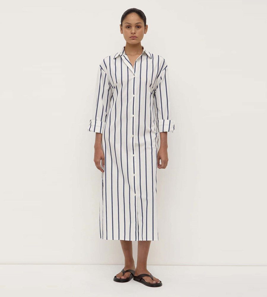 Woman wearing a long black and white striped shirt dress on a white background