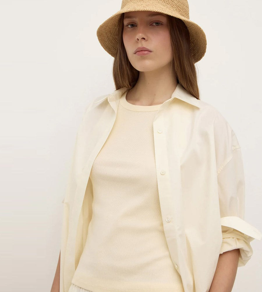 Woman wearing a beige hat and light-colored shirt against a plain background
