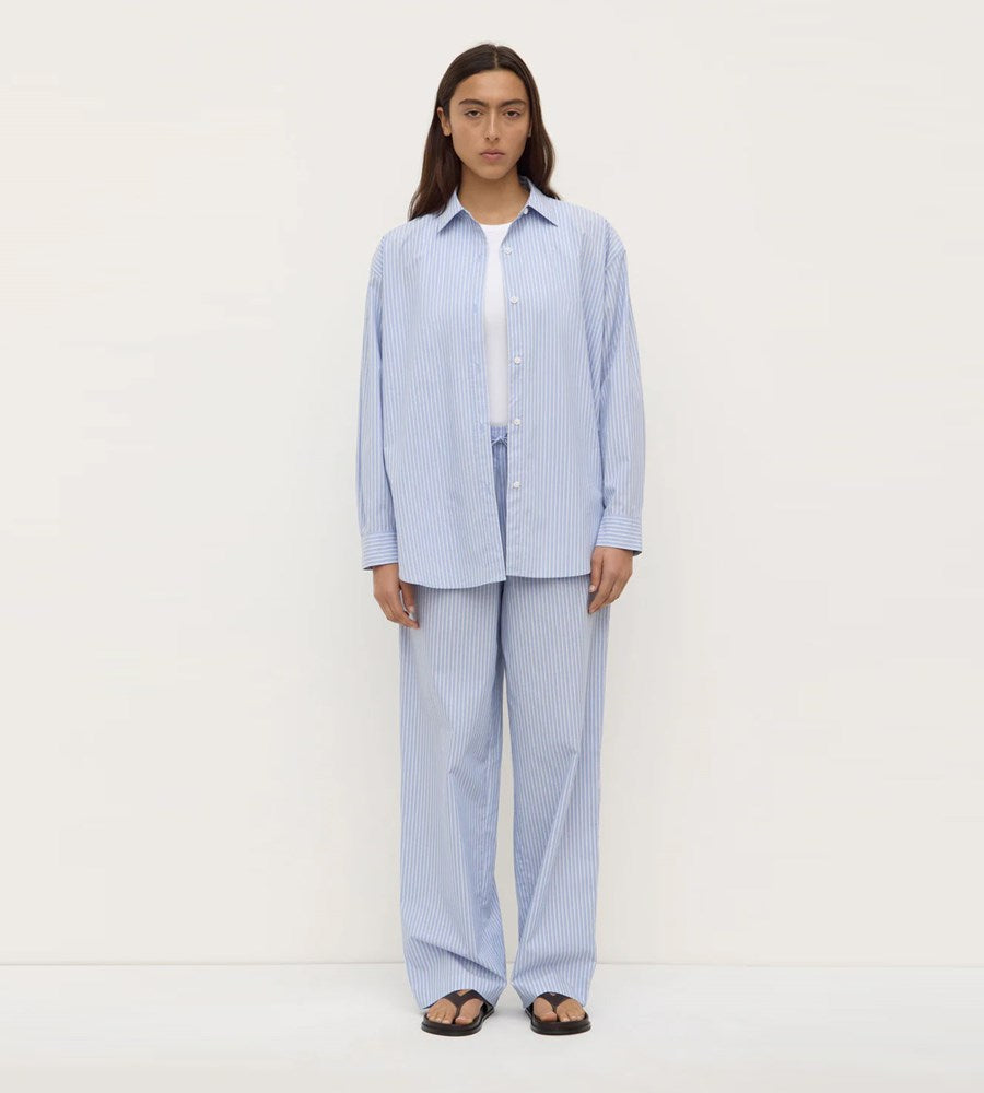Person wearing a light blue striped shirt and pants on a white background