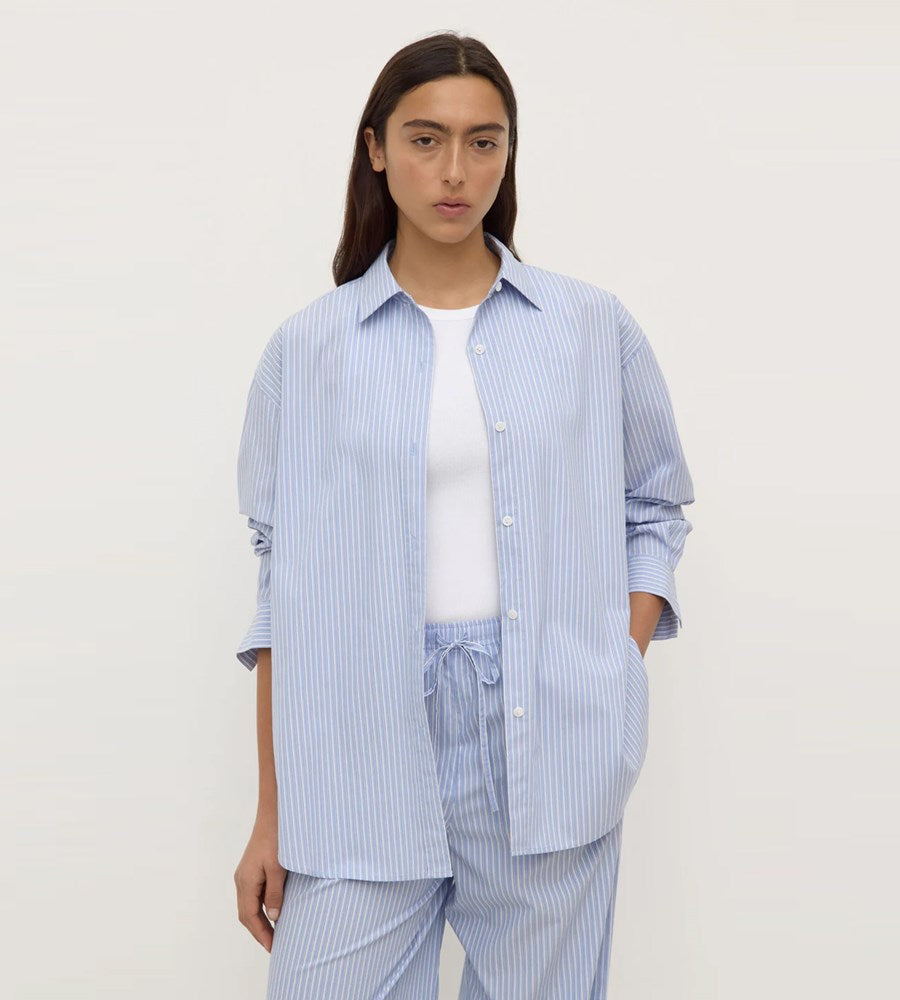 Person wearing a light blue striped shirt and pants on a white background