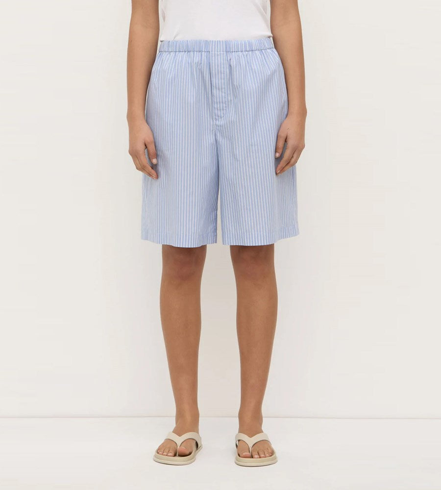 Person wearing light blue striped shorts on a white background