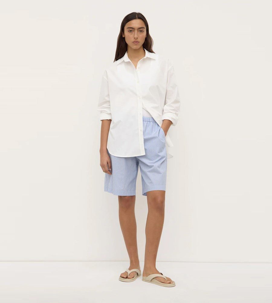 Woman wearing a white shirt and blue shorts on a white background