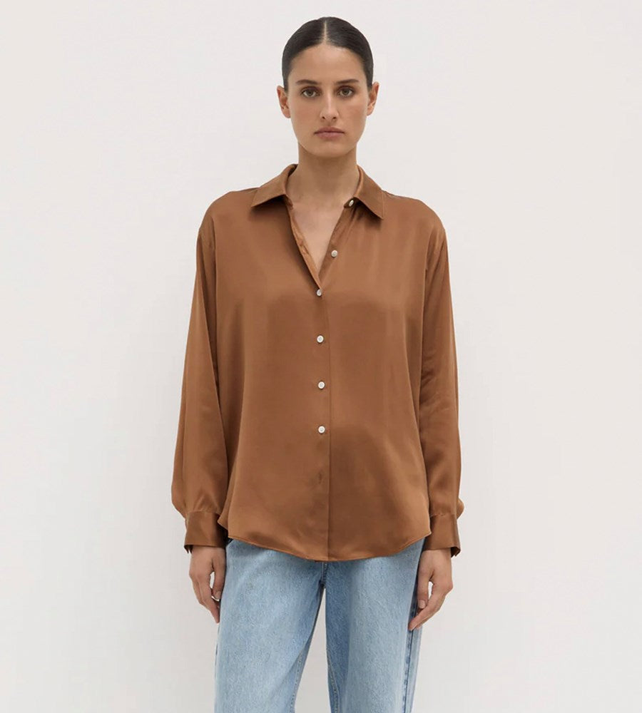 Woman wearing a brown shirt and light blue jeans on a white background