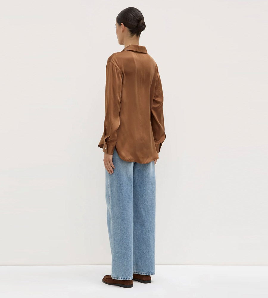 Person wearing a brown shirt and blue jeans on a white background