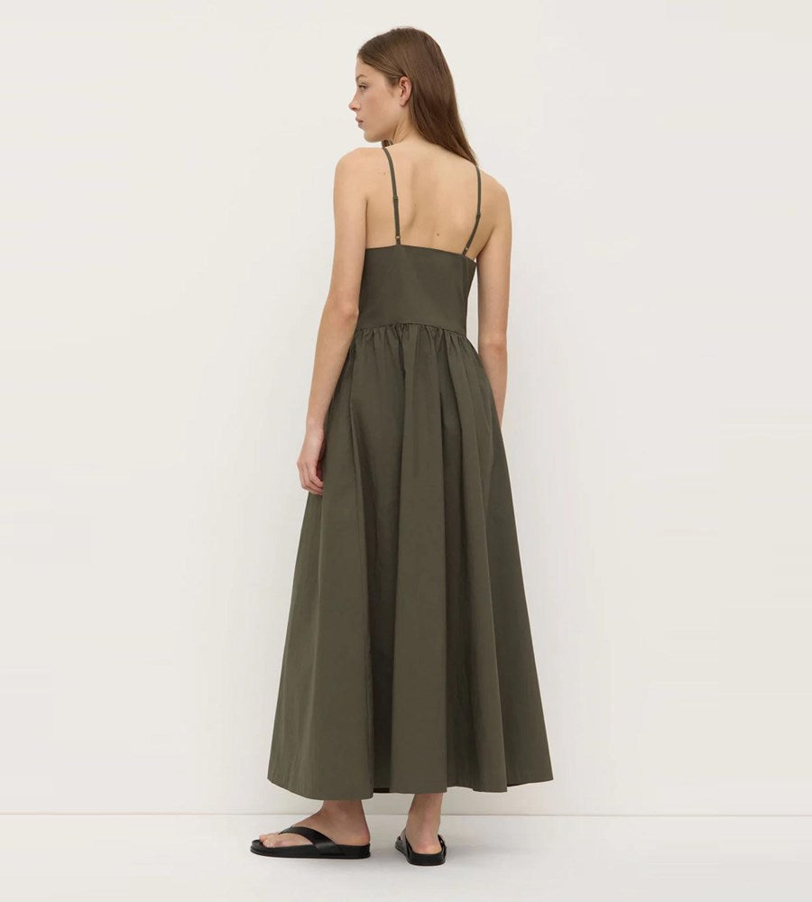 Woman wearing a long olive green dress against a white background