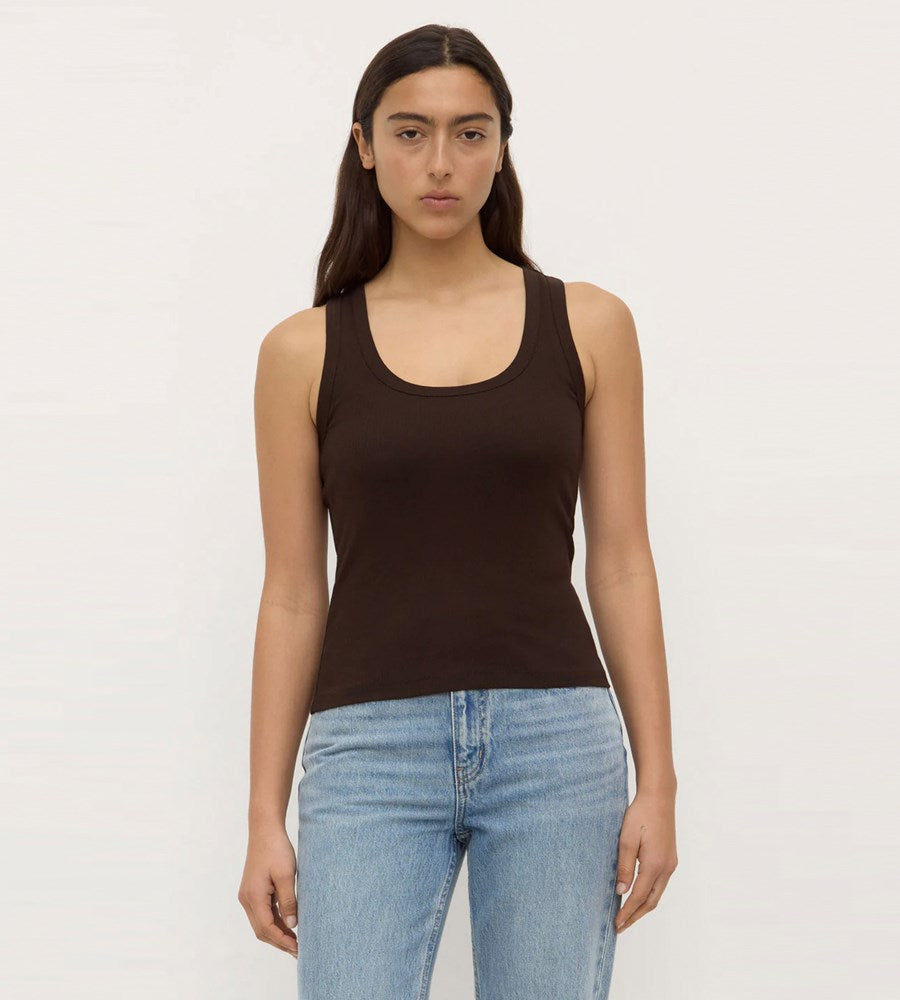 Woman wearing a brown tank top and light blue jeans on a white background