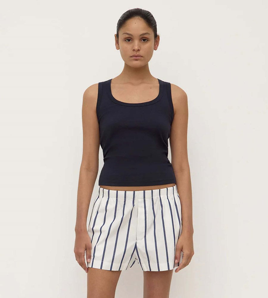 Woman wearing a black tank top and striped shorts on a white background