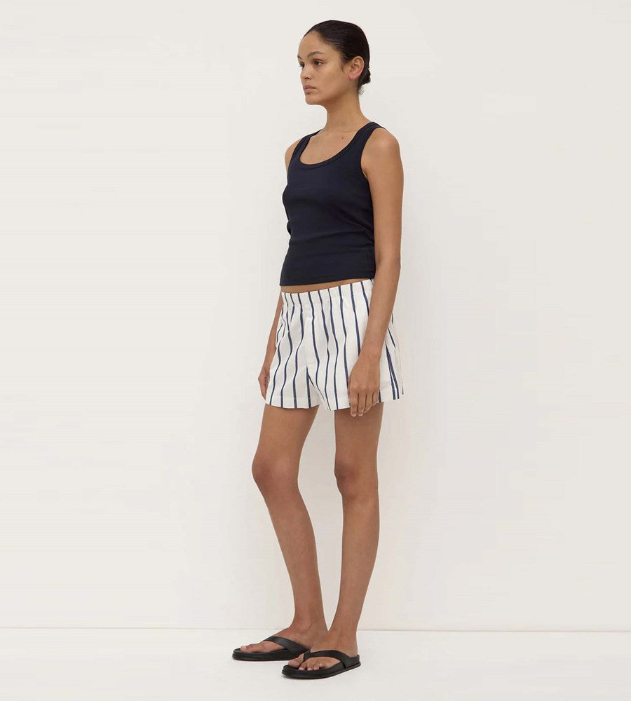 Woman wearing a black tank top and striped shorts on a white background