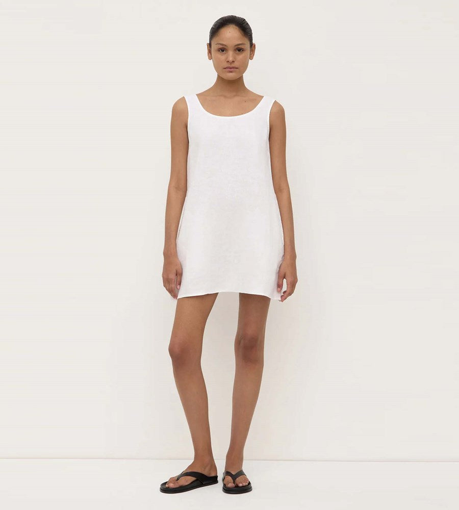 Woman wearing a white sleeveless dress against a plain background