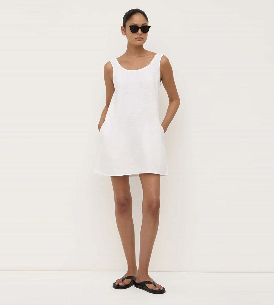 Woman wearing a white sleeveless dress against a plain background