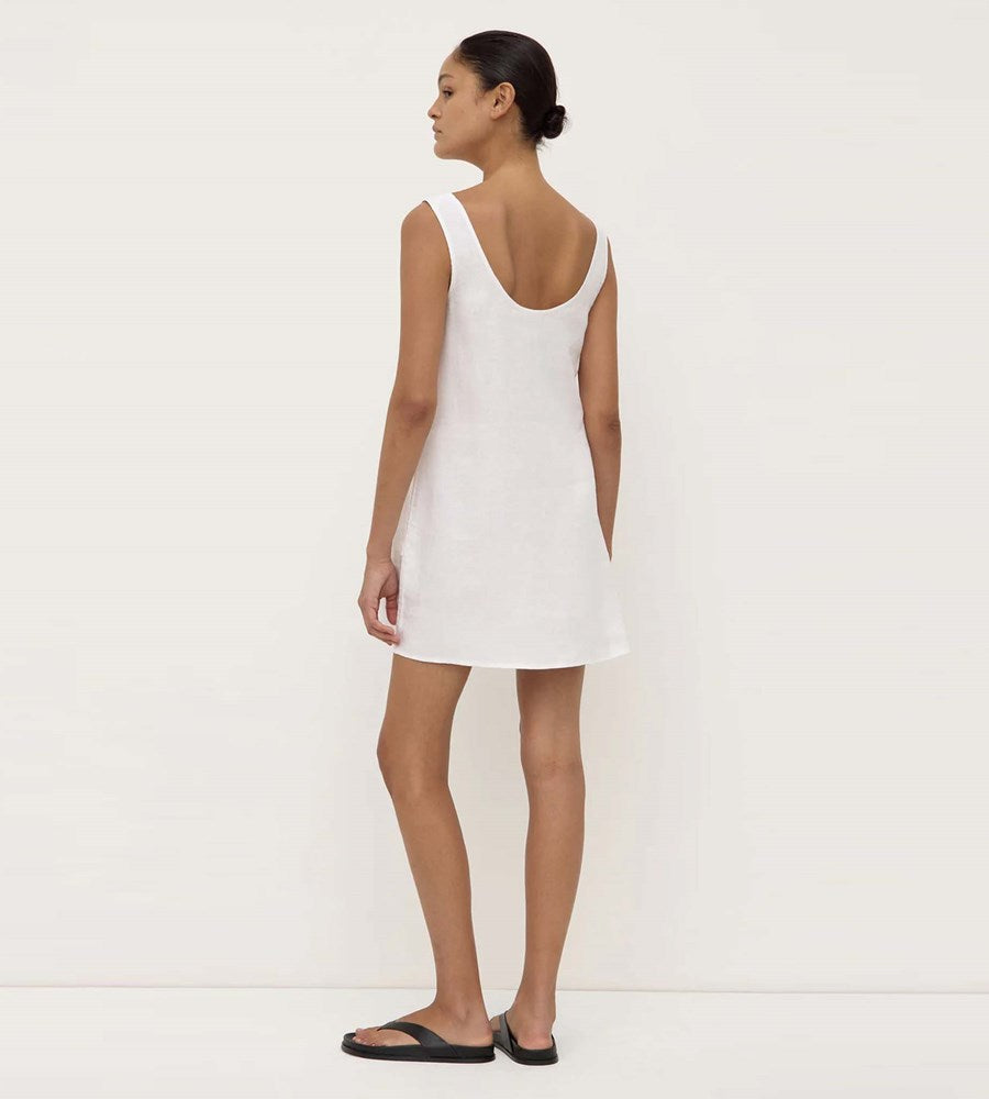 Woman wearing a white slip dress against a plain background