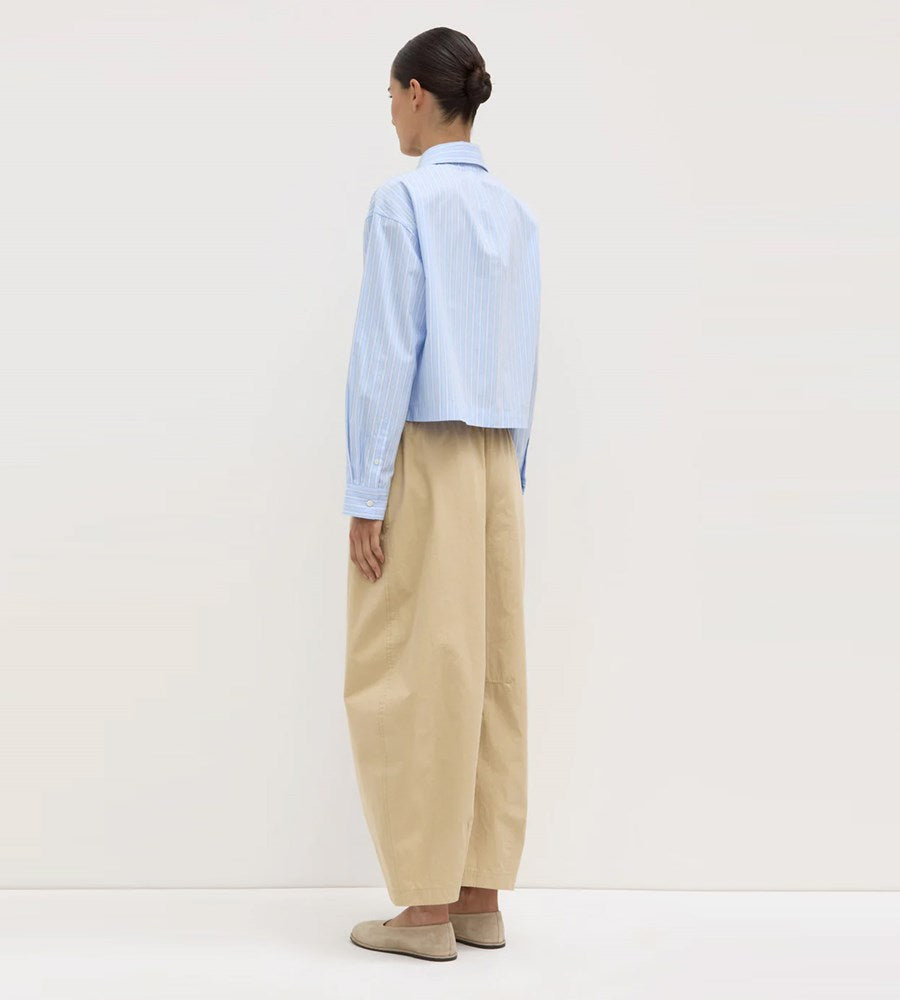 Person wearing a light blue shirt and beige pants on a white background