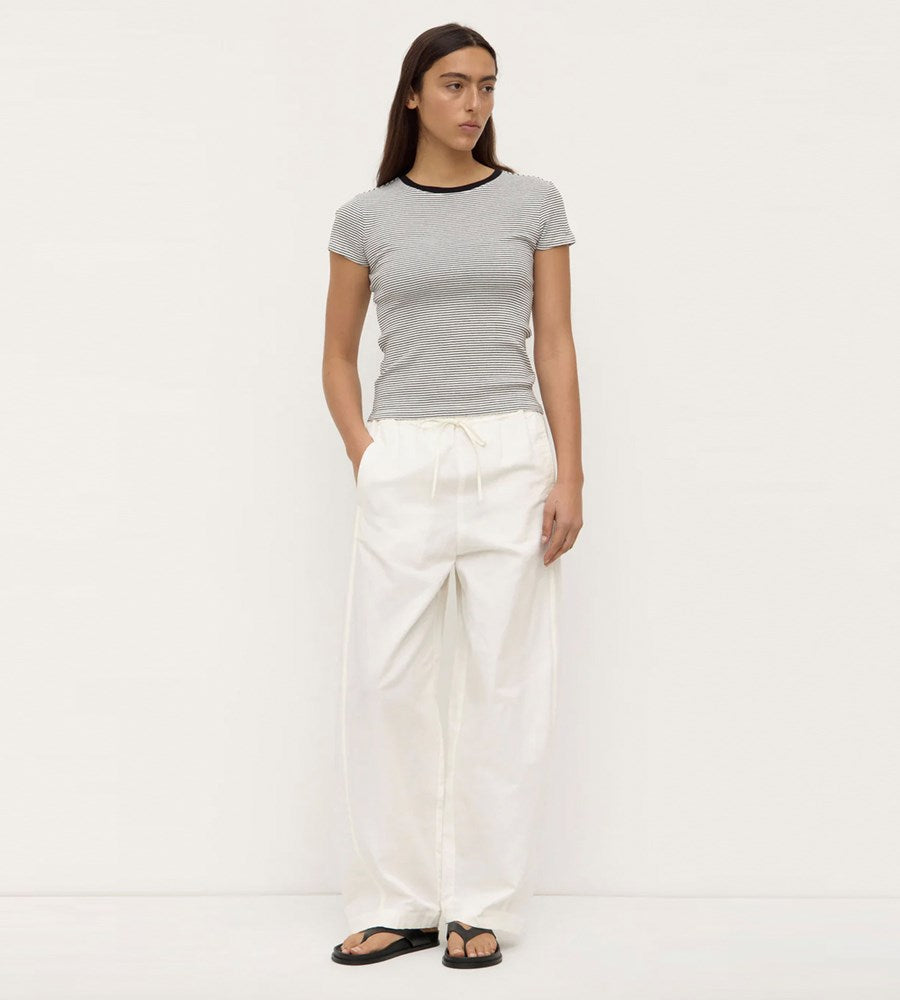 Woman wearing a gray t-shirt and white pants on a white background