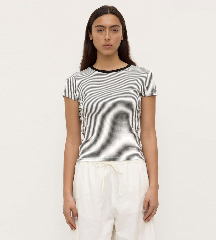 Woman wearing a striped shirt and white pants on a plain background