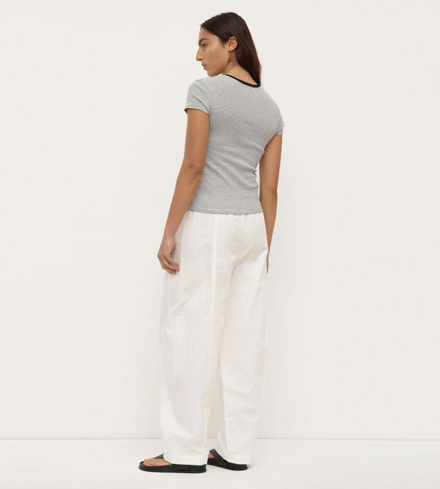 Woman wearing a gray t-shirt and white pants on a plain background