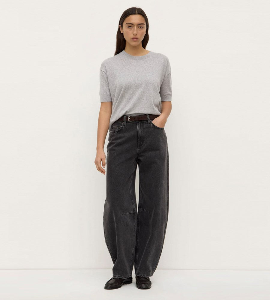 Person wearing a gray sweater and black pants on a white background