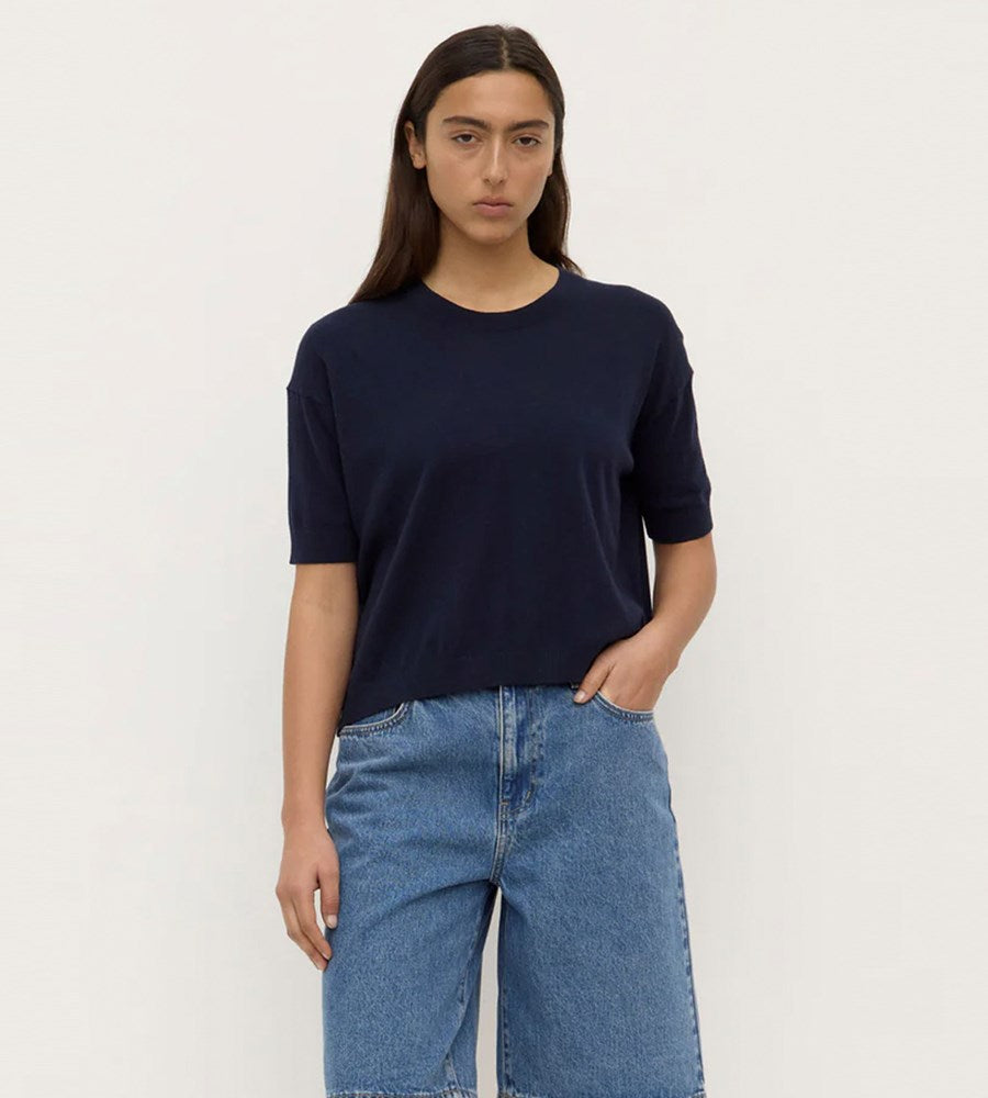 Person wearing a navy blue t-shirt and blue jeans on a white background