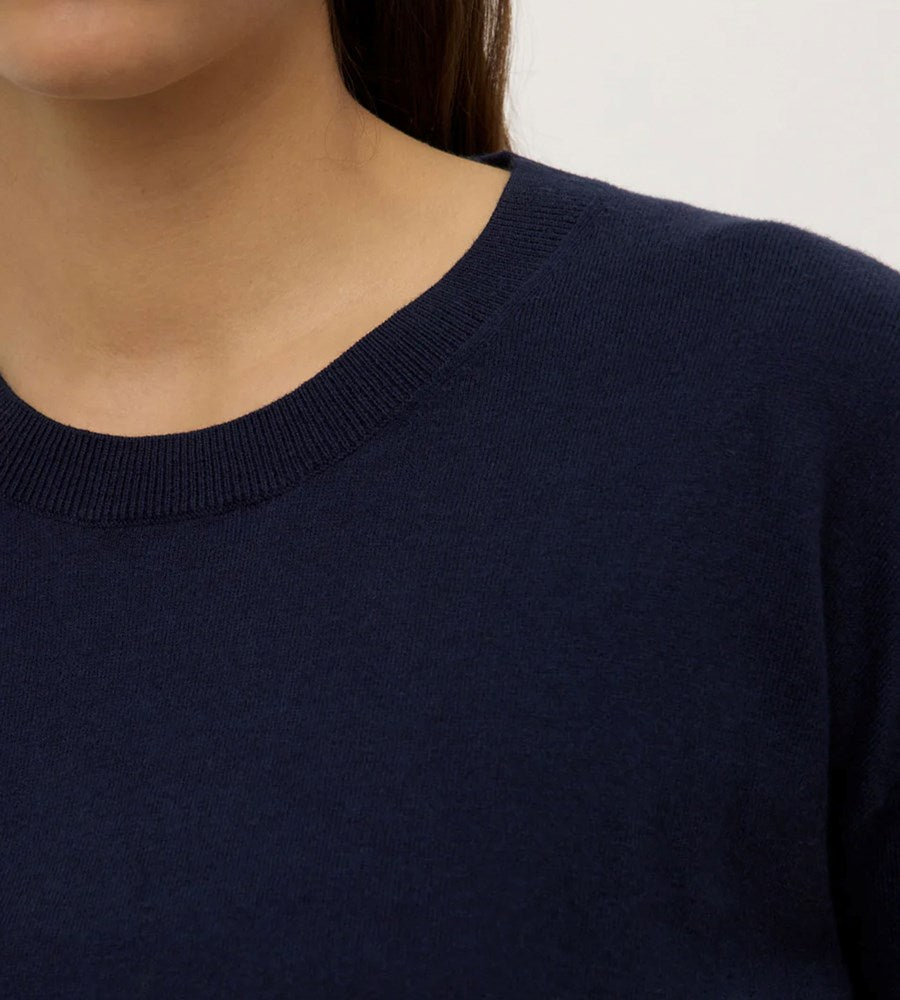 Navy blue sweater worn by a person on a plain background