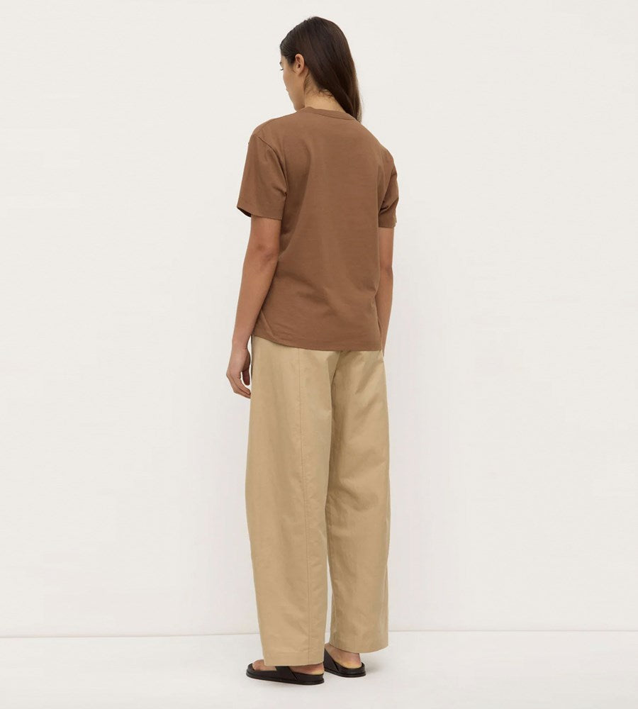 Person wearing a brown t-shirt and beige pants on a white background