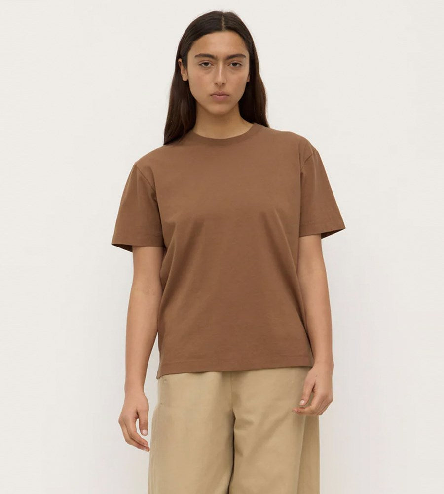 Person wearing a brown t-shirt and beige pants on a white background