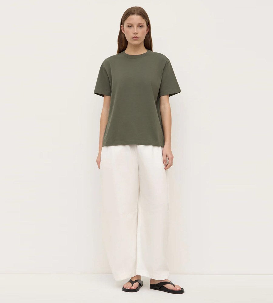 Person wearing a green t-shirt and white pants on a white background