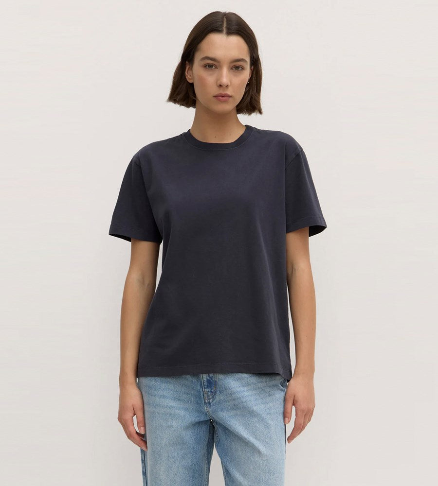 Person wearing a dark blue t-shirt and light blue jeans on a plain background