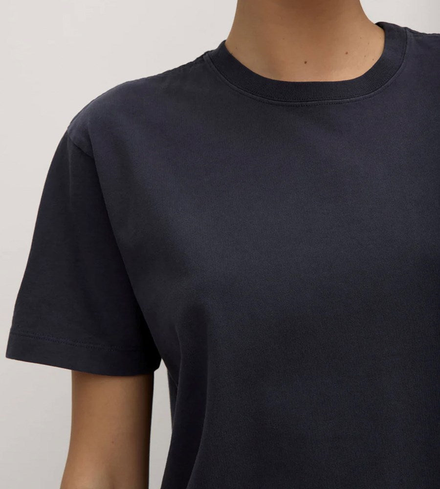 Black t-shirt worn by a person on a plain background