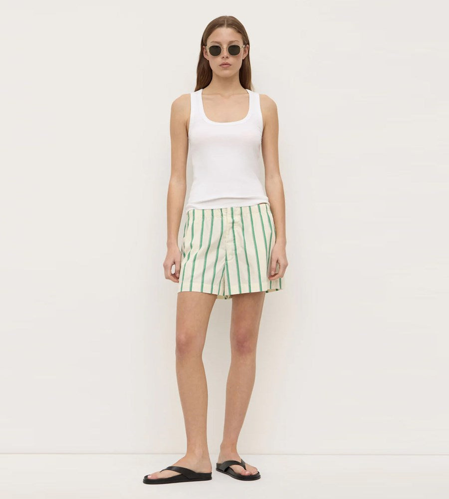 Woman wearing a white tank top and green striped skirt on a plain background