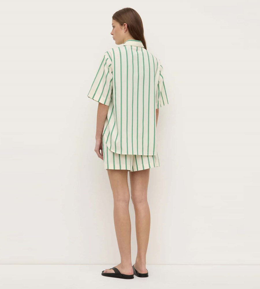 Woman wearing a green and white striped outfit on a plain background