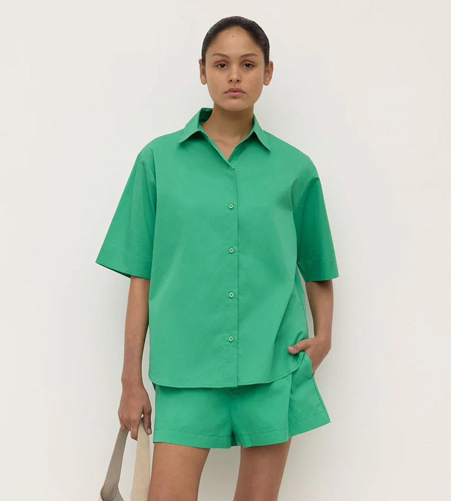 Person wearing a green shirt and shorts set on a white background